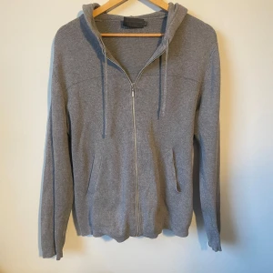 Stickad Full zip hoddie - Säljer en stilren grå hoodie från New Urban Khakis. Den är i ett skönt material. Den passar dig som är runt 180cm. Skicka om du har frågor eller funderingar 