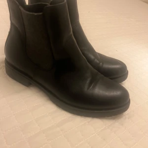 Svarta chelsea boots - Snygga svarta chelsea boots i skinn med elastiska paneler på sidorna för enkel på- och avtagning. Perfekta för både vardag och mer uppklädda tillfällen.