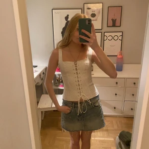 Vit randig korsett med snörning - Snygg vit korsett med tunna svarta ränder och snörning framtill. Perfekt för en stilren look med breda axelband och en figurnära passform.(ny med prislapp kvar)