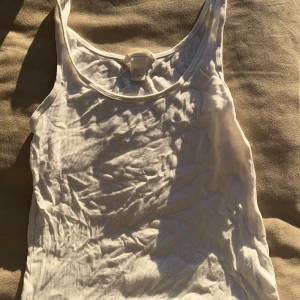 Vit ribbad linnetopp från Basic - Säljer en enkel och stilren vit ribbad linnetopp från Basic. Perfekt för varma dagar eller som lager under andra plagg. Linnet har en klassisk design med rund halsringning.