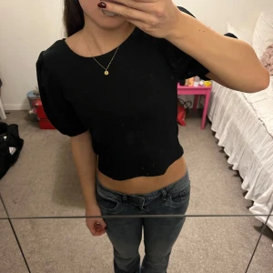 Svart croppad topp - Snygg svart croppad topp med korta puffärmar. Perfekt för en trendig look. Enkel och stilren design som passar till många olika outfits. (Köpt gör 150kr)