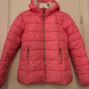 Rosa pufferjacka från Next  - Säljer en rosa pufferjacka från Next med dragkedja och huva. Jackan har en mysig fleecefoder på insidan av huvan och jackan och praktiska fickor med dragkedja. Perfekt för kyliga dagar! Är lite smutsig på ärmarna men går säkert att ta bort. Säljer även en halsduk och en mössa som skulle passa till! Går att köpa till. 