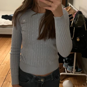 Ljusblå stickad tröja från Gina Tricot - Säljer en ljusblå stickad tröja från Gina Tricot med kabelstickat mönster. Tröjan har långa ärmar och en rund halsringning. Storlek: XS