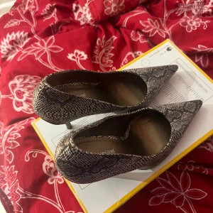 Ormskinnsmönstrade pumps från Graceland - Snygga pumps med ormskinnsmönster från Graceland. Skorna har en spetsig tå och hög klack, vilket ger en elegant look. Perfekta för att lyfta vilken outfit som helst.