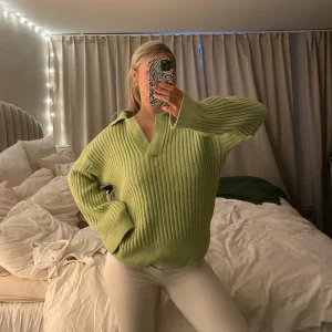 Grön ribbad tröja med krage - Säljer en mysig grön ribbad tröja med krage och v-ringning. Perfekt för kyliga dagar och ger en avslappnad stil. Tröjan har långa ärmar och en lös passform.