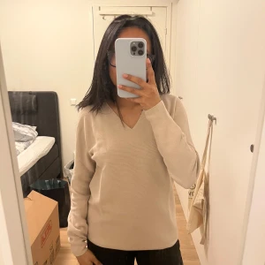 Beige tröja från Uniqlo - Säljer en stilren beige tröja från Uniqlo i storlek S. Tröjan har en v-ringad design.