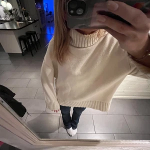 Beige/vit polotröja - Säljer en supermysig beige polotröja i oversized modell. Perfekt för kalla dagar med sin tjocka, stickade kvalitet och ribbade detaljer vid ärmslut och nederkant. Tröjan har en hög polokrage som håller dig varm och stilren. Passar perfekt till jeans eller leggings för en avslappnad look. 🧶✨
