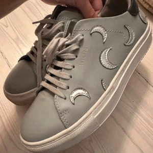 Arigatos  - Använda Max 4 gånger !                                            Pris kan diskuteras! Snygga grå sneakers från Axel Arigato med coola silverfärgade måndetaljer. Perfekta för både vardag och festliga tillfällen. De är i mycket bra skick!! 