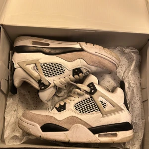 Nike Air Jordans i vit och svart - Säljer ett par klassiska Nike Air Jordans i vit och svart med snygga detaljer. Skorna har snörning och en ikonisk design med nätpaneler och Jumpman-logga på plösen. Perfekta för sneakerheads som vill ha en tidlös stil.
