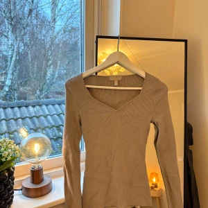 Beige ribbad tröja från H&M - Säljer en snygg beige ribbad tröja från H&M. Den har en v-ringad hals och långa ärmar,  Tröjan är i bra skick. Fin passform 