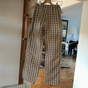 Bruna rutiga byxor - Säljer ett par bruna rutiga byxor i normal passform som jag själv har sytt. Tyvärr har jag själv tröttnat på mönstret trots att passformen sitter perfekt! De är raka och långa. Passar mig som är stl w25 l32/34. De har en dragkedja bak och i bra skick! 