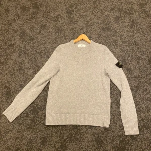 Grå stickad tröja från Stone Island - Säljer en stilren grå stickad tröja från Stone Island. Tröjan har långa ärmar och en klassisk rund halsringning. Skick 10/10 