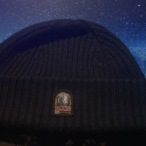 Svart ribbad mössa från Parajumpers - Säljer en snygg svart ribbad mössa från Parajumpers. Den är perfekt för kalla dagar och har en stilren design med ett märke framtill. Mössan är i storlek S-M och passar de flesta. Håll dig varm och trendig i vinter! 🖤självklart äkta