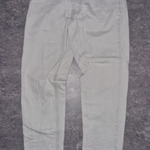 Zara jeans 38 EUR - Säljer ett par snygga beige byxor från Zara i storlek EUR 38. De är i bra skick och perfekta för både vardag och fest. Byxorna har en klassisk design med knapp och dragkedja framtill. Passar bra till en avslappnad stil eller kan kläs upp för mer formella tillfällen.