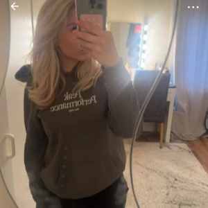 Grå grön hoodie från Peak Performance - Säljer en stilren grå grön hoodie från Peak Performance med tryck på bröstet. Perfekt för en avslappnad look. Den har en klassisk huva och en bekväm passform.