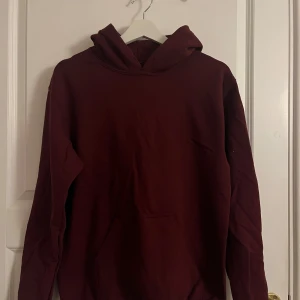 Vinröd hoodie - Säljer en mysig vinröd hoodie med luva och magficka. Perfekt för kyliga dagar och avslappnade stunder. Passar bra till jeans eller mjukisbyxor. Hör av dig vid intresse! OBS! Det saknas band till luvan, men jag tycker den ser bättre ut utan! 