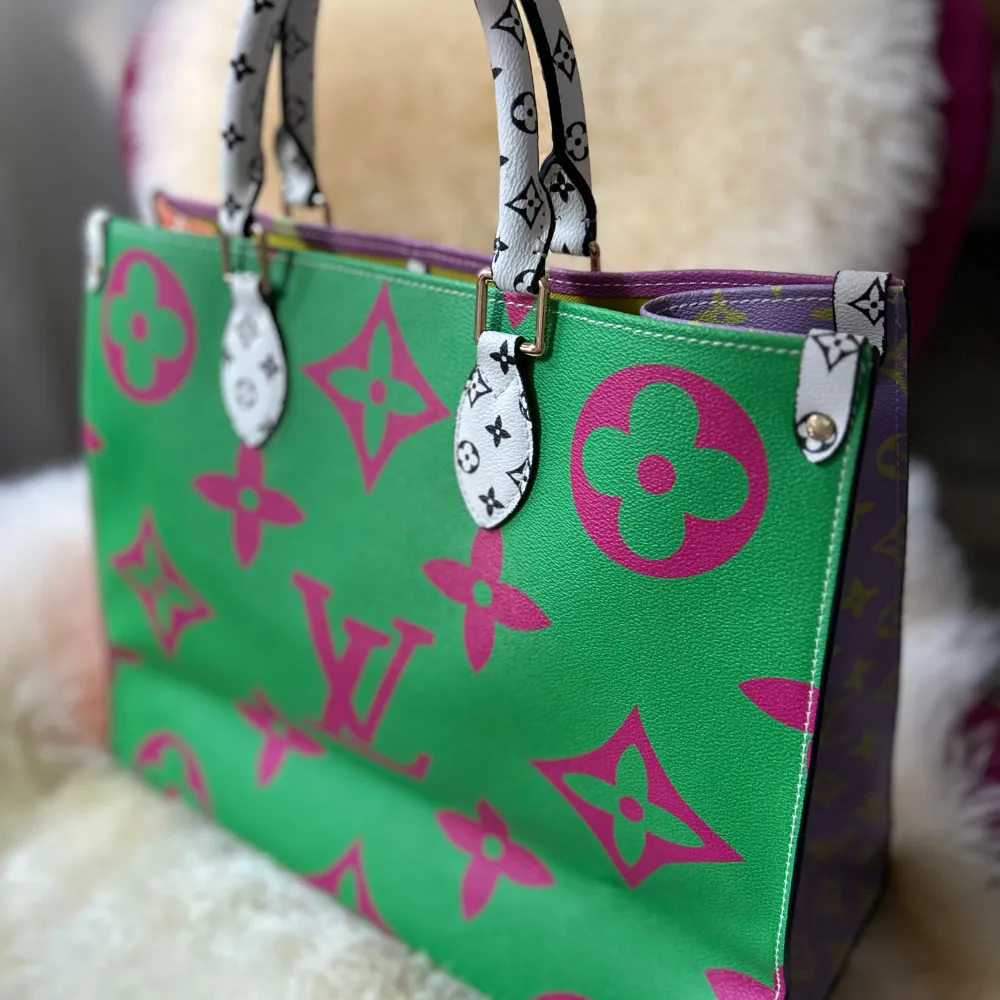Säljer en supercool handväska med ett färgglatt monogrammönster. Väskan har en mix av lila, grönt och gult med vita handtag. Insidan är ljusgul och har en praktisk ficka. Perfekt för att liva upp vilken outfit som helst!. Laukut & Käsilaukut.