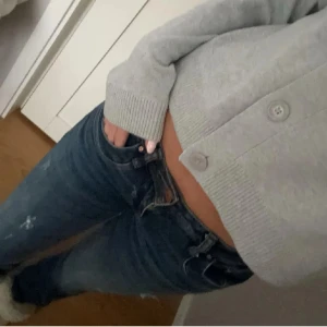 Blå jeans med slitningar - Säljer ett par snygga blå jeans med coola slitningar. De har en låg midja och är bootcut. Perfekta för vardagsbruk eller en casual utekväll. Dragkedja och knapp framtill. Dom har ett litet hål vid högre delen av låret men syns knappt när dom är på.
