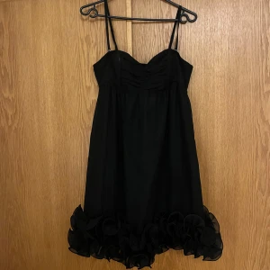 Svart klänning med volangdetaljer - Säljer en söt svart klänning med smala axelband och vackra volangdetaljer längst ner. Perfekt till jul/nyår! Den har avtagbara axelband. Säljer pga lite stor för mig. Köpt på sellpy förra året. Den är från HM i storlek 36!❤️ 