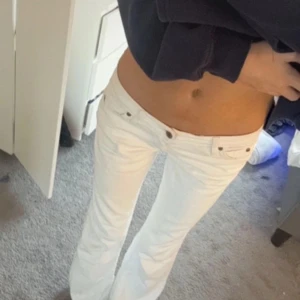 Vita bootcut jeans - Skit snygga vita lågmidjade bootcut jeans, med mönster på bakfickorna, knappt använda.