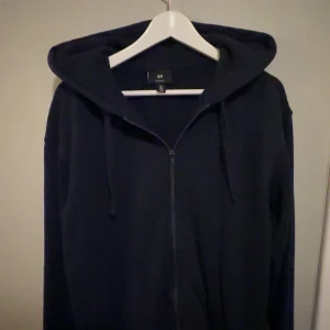 Mörkblå zip hoodie - Säljer en stilren svart hoodie från H&M i bra skick. Den har en dragkedja framtill och en skön huva med dragsko. Perfekt för både vardag och mysiga kvällar. Passar till allt och är superbekväm!