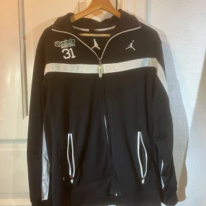 Svart och vit Jordan jacka - Säljer en snygg svart och vit Jordan jacka i storlek S. Den har en dragkedja framtill och coola vita detaljer. Perfekt för basket eller chill vardagsstil. Jackan är i bra skick och har långa ärmar med en sportig look. Passar perfekt för höst och vår!