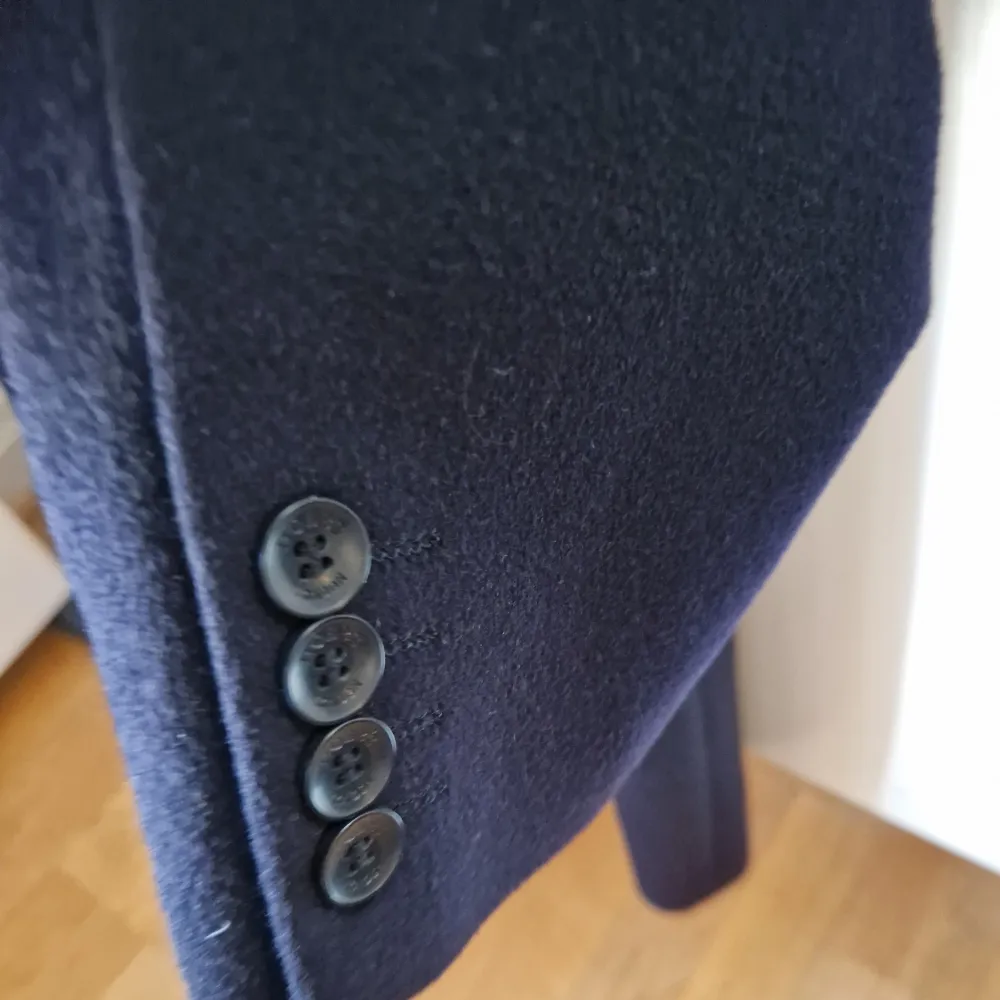 En elegant kappa i mörkblå färg med en enkel och klassisk design. Kappan är i gott skick och har inte använts mycket. Brand: HOBBS Storlek: 36  Model: Tilda wool coat Färg: Navy Dry clean only 100% Wool/ Ull Nypris i butiken: 4250Kr . Jackor.