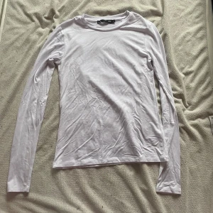 Vit långärmad tröja - Säljer en enkel och stilren vit långärmad tröja. Perfekt för lager-på-lager under kyligare dagar. Tröjan är i ett mjukt och bekvämt material, vilket gör den idealisk för vardagsbruk. Passar bra till både jeans och kjol!