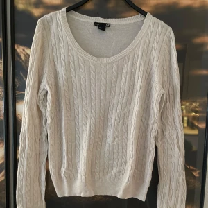 Vit stickad tröja från H&M - Säljer en superfin vit stickad tröja från H&M. Den har ett klassiskt flätmönster och är perfekt för kyliga dagar. Tröjan är långärmad och har en rund halsringning. Passar både till vardags och lite finare tillfällen. Perfekt för höst och vinter! 🍂❄️