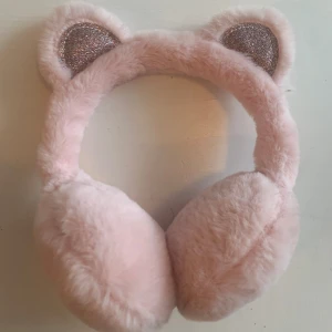 Rosa fluffiga öronmuffar med kattöron - Supergulliga rosa öronmuffar i fluffigt material med glittriga öron. Perfekta för att hålla sig varm och söt nu när det är kyligt🌼✨I utmärkt skick och är i one size. Vid köp av muffarna får man ett gratis halsband :) Priset kan diskuteras och om fler bilder begärs kontakta bara mig!