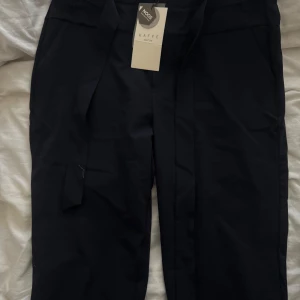 Mörkblå kostymbyxor  - Mörkblå kostymbyxor med band i storlek 42 helt oanvända. Finns att hämtas i Lidköping. Betalas med swish