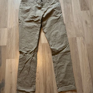 Beige chinos - Säljer ett par klassiska beige chinos i normal passform. De har knappar och dragkedja framtill samt fickor både fram och bak. Perfekta för både vardag och lite mer uppklädda tillfällen. Passar bra till höst och vår!