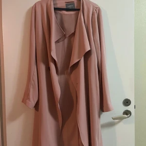 Rosa trenchcoat från Lindex - Säljer en superfin rosa trenchcoat från Lindex i storlek S. Den har långa ärmar och ett bälte i midjan för en snygg passform. Perfekt för vår och höst! 💖