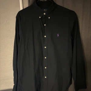 Ralph lauren skjorta  - Skjorta från Ralph lauren i bra skick. Storlek L, slim fit. Svart färg med lila polo logga. 