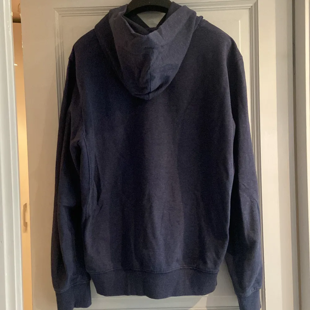 En gråblå/mörkblå hoodie från Tommy Jeans med snygga detaljer (broderat märke på armen och bröstet och ”ribbat” på sidorna), bra skick. Hoodies.