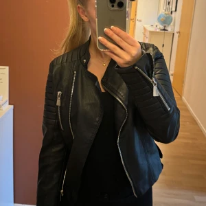 Svart skinnjacka - Svart skinnjacka från Voyelles i storlek 38. Många detaljer med dragkedjor och likande. Bra skick.