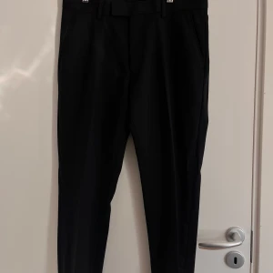 Svarta kostymbyxor från Riley - Säljer ett par stiliga svarta kostymbyxor från Riley. Byxorna är tillverkade av en blandning av polyester och elastan för en bekväm passform. Perfekta för både formella tillfällen och kontoret. 🖤