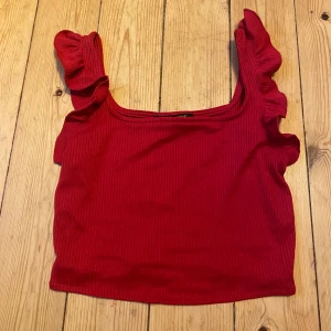 Röd top - Röd top i ribbat material med volanger på axelbanden. Lappen är bortklippt men ganska säker på att den är i storlek S. Använd en gång så i fint skick💗