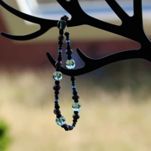 Pärlarmband med gröna och svarta pärlor - Säljer ett snyggt armband med en mix av gröna och svarta pärlor. Armbandet har en cool design med genomskinliga gröna pärlor som ger en fräsch look. Perfekt för att piffa upp vilken outfit som helst!