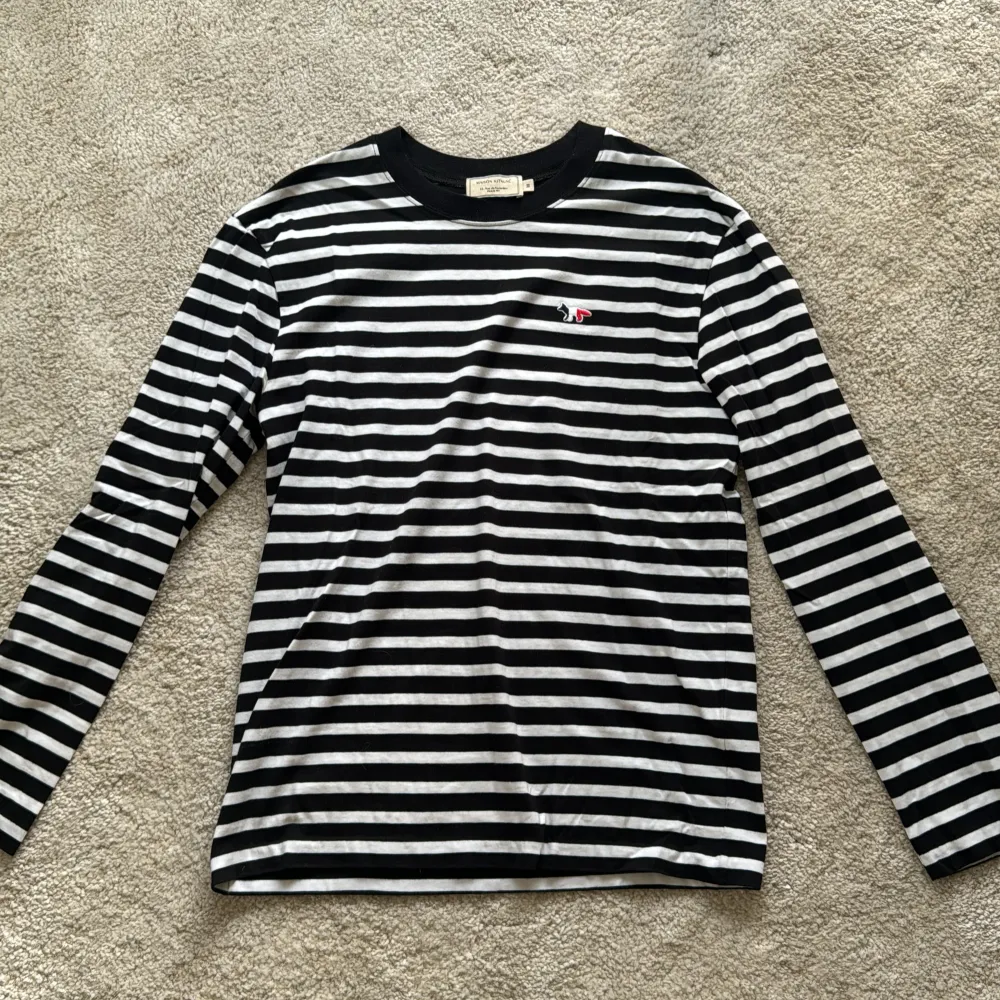 Maison Kitsuné tröja med randigt mönster i svart och vit med Maison Kitsuné logga på vänster bröst. Nypris 149 euro. Inköpt i Maison Kitsuné butik i Paris. Använd och tvättad en gång och därför i felfritt/nyskick.. T-paidat.
