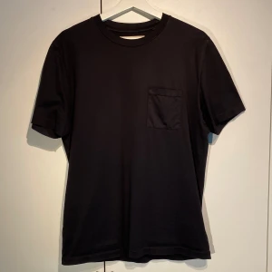 Our Legacy Pocket t-shirt  - Hej, säljer en schysst t-shirt från Our Legacy med bröstficka. Storlek 46 men passar Medium. Avslappnad passform. Grymt bra basplagg, passar till allt. Nypris 1500kr. Använd men fin. Härligt material och grym kvalite. Pris kan diskuteras. Hörs i DM! 