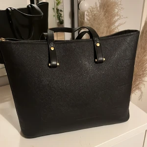 Väska - Jättefin svart väska från hm som inte kommer till användning längre. Perfekt att ha som skolväska då den rymmer mycket. Handtagen på väskan är ganska slitna, annars finns det inga andra defekter.🤍