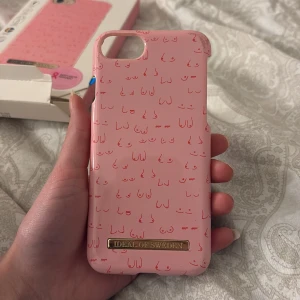 Rosa mobilskal från iDeal of Sweden - Säljer ett rosa mobilskal från iDeal of Sweden med ett unikt mönster i samarbete med ”bröstcancer förbundet”. Skalet är designat för iPhone 8/7/6/6S och har en stilren look med en liten metallplatta med varumärkesloggan. Perfekt för att ge din mobil en fin och personlig touch! Lite defekter på skalet (syns på bilderna), därav priset!