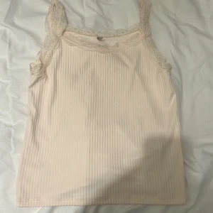 Beige ribbad linnetopp från Only - Säljer en söt rosa linne från Only med spetsdetaljer vid axelbanden och halsringningen. Storlek 146-152 men passar mig som bär s-m vanligtvis. Nypris är 399.