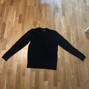 Svart tröja från Dressmann - Säljer en stilren svart tröja från Dressmann i storlek M. Tröjan har en klassisk design med långa ärmar och rund hals. Perfekt för en enkel och snygg look.