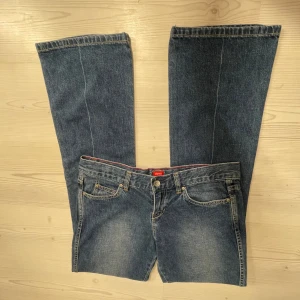 Blå Lågmidjade bootcut jeans - Snygga blå bootcut jeans med klassisk femficksdesign och knappgylf. Midjemåttet 40, Innerbenslängd 83 och grenmått 20. Jag är 167💗
