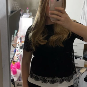 Svart spetsblus - Elegant svart spetsblus med korta ärmar och vackra spetsdetaljer. Perfekt till både vardags och festligare tillfällen. Lappen är tyvärr bortklippt men den passar mig som brukar ha S/M 