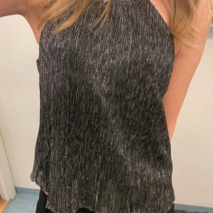 Svart / grå glittrig topp  - Super snygg svart / grå glittrig topp från H&M, perfekt för fest o finare tillfällen. Säljer då den tyvärr inte kommer till användning längre, storlek 34 men passar mig som brukar ha S 