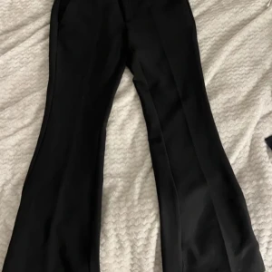 Svarta kostymbyxor från Gina Tricot - Snygga svarta byxor från Gina Tricot i storlek 38. Byxorna har en bootcut-stil och är perfekta för en stilren look.