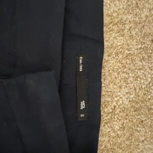 Svarta byxor från 157 - Snygga svarta byxor i bra skick från Lager157. Byxorna har en rak passform och en enkel, elegant design. Perfekta för både vardag och festligare tillfällen.  Kombinerat kappan med alla typer av kläder och den passar till nästan allt Märke: lager157 Storlek :S Skick: 8/10 Ord. Pris: 299 SEk Litet märke som går bort i tvätten  Din stil: spara inlägget så du inte missar denna kappa Inte din stil: Kolla min profil. Du kommer hitta något för alla kön och åldrar.